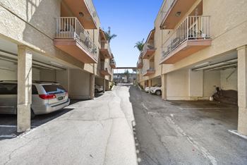 A car is parked in a garage under a building with a balcony.